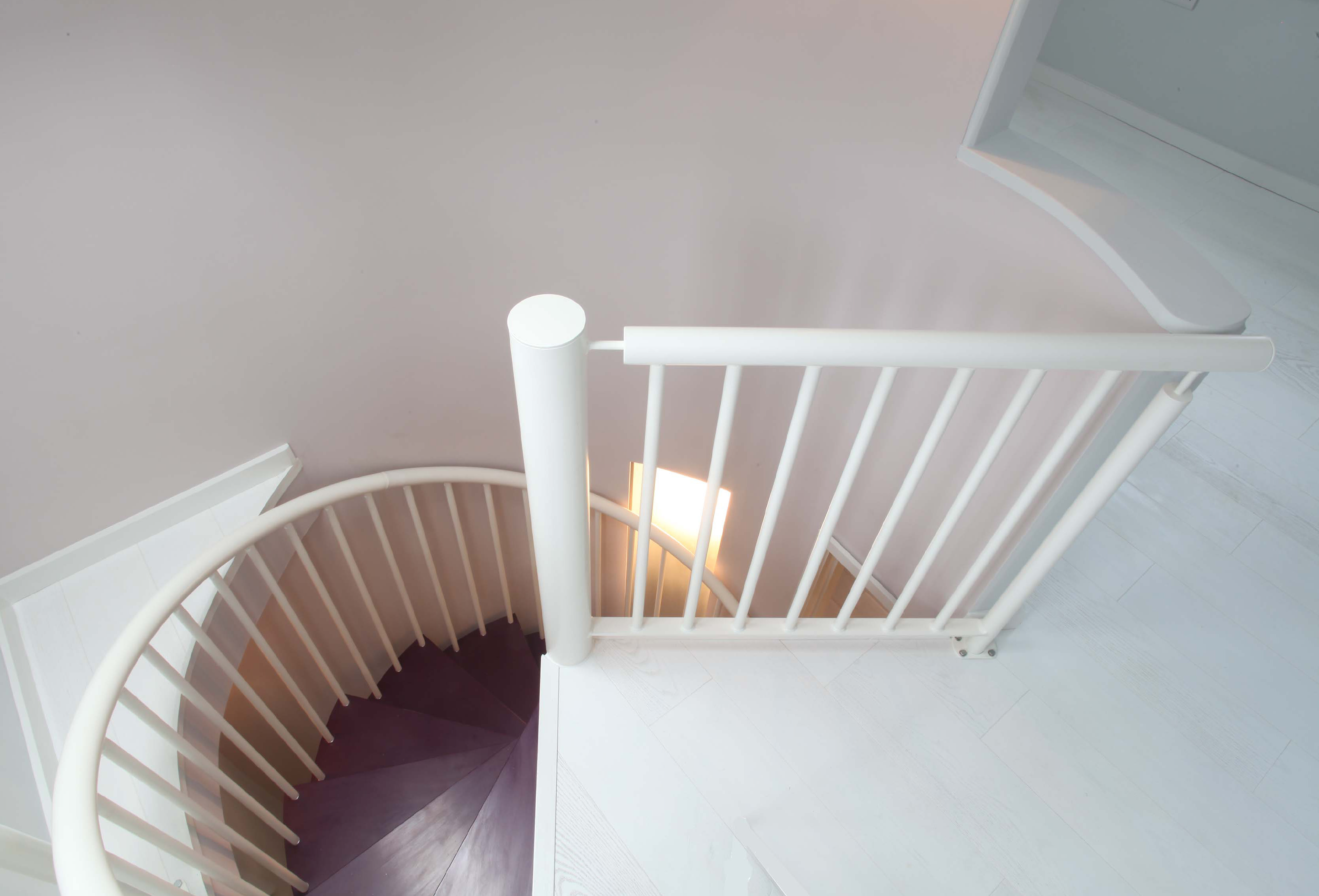 Photograph of a white spiral staircase looking down the stairwell from the top floor.